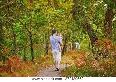 Father Carrying His Shild During Walk In Forest. Man With His Adorable Toddler Daughter Enjoying Nat
