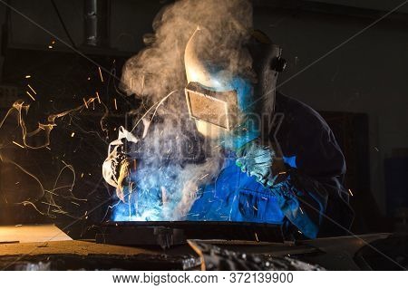 Electric Welder Working With Argon Welding, A Welder Wearing A Mask While Working On Detail
