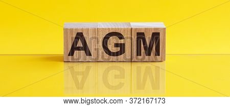Agm - Annual General Meeting - Acronym On Wooden Cubes On Yellow Backround. Business Concept.