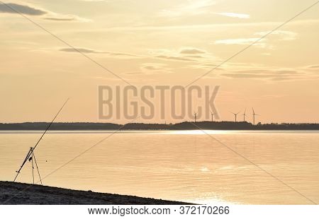 Fishing At Sunset In The Eckernförde Bay, In Northern Germany. The Dark Silhouette Of A Fishing Pole