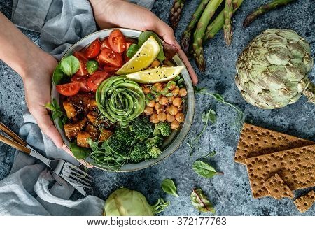 Hands Holding Healthy Superbowl Or Buddha Bowl With Salad, Baked Sweet Potatoes, Chickpeas, Broccoli