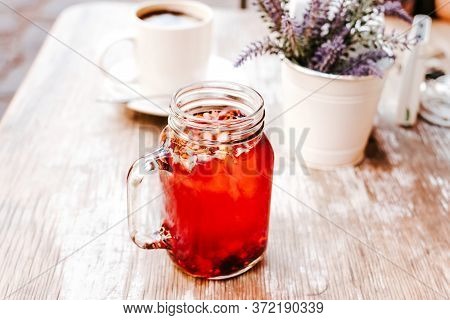 Tisane Or Red Herbal Tea In A Transparent Glass Jar On A Table Outdoors In A Tea House In The Street