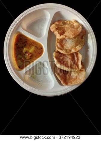 Puri And Potato Curry Aalu Sabji - An Indian Cuisine In Round Plate Isolated On Black Dark Backgroun