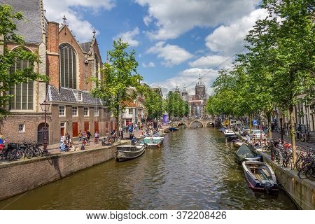 Amsterdam, Netherlands - 31 May, 2014: Tourists Walking By A Canal In Amsterdam. Amsterdam Is The Ca
