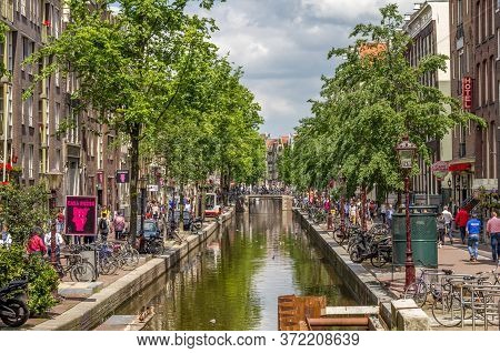 Amsterdam, Netherlands - 31 May, 2014: Tourists Walking By A Canal In Amsterdam. Amsterdam Is The Ca