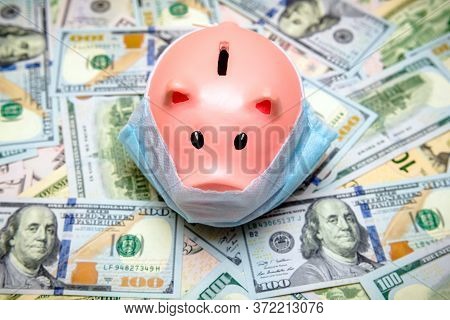 Piggy Bank In A Mask On A Background Of American Currency.the Concept Of Coronavrius Epidemic
