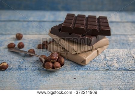 A Piece Of Chocolate With Hazelnuts And Nuts On A Table