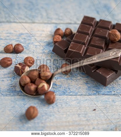 A Piece Of Chocolate With Hazelnuts And Nuts On A Table