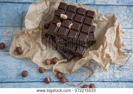 A Piece Of Chocolate With Hazelnuts And Nuts On A Table
