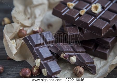 Craft Piece Of Chocolate With Hazelnuts And Nuts On A Table