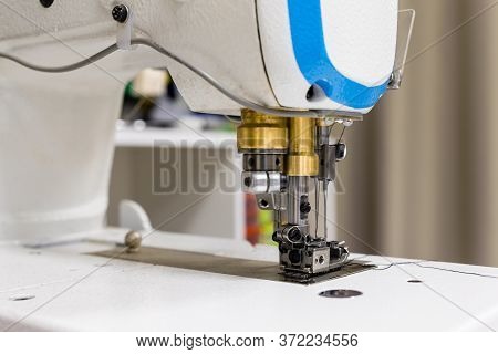 A Professional Sewing Machine Is In The Workshop. Against The Background Of Various Devices And What