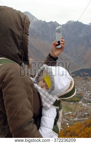 Portrait Of Young Mother With Her Little Sleeping Girl In Ergo Carrier On A Background Of Autumn Mou