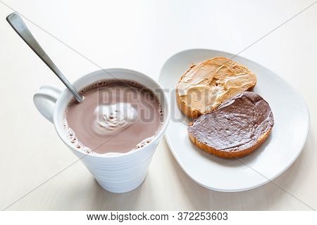 Top View Of Mug With Hot Chocolate And Toasts With Peanut Butter And Chocolatte Spread On Plate On T