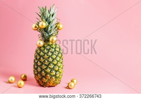 Golden Christmas Balls On Pineapple, Pink Background. Pineapple Like A Christmas Tree. Travel Concep