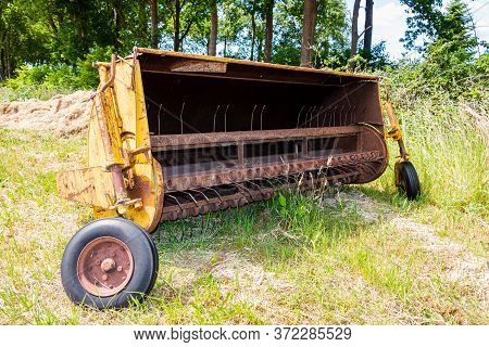 Vintage And Old-fashioned Yellow-painted Hay Tedder On Land, Partly Rusted By Age