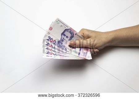 Female Hand Holds A Thousand Hryvnia. Ukrainian Currency With Woman's Hand Against A White Backgroun