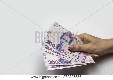 Female Hand Holds A Thousand Hryvnia. Ukrainian Currency With Woman's Hand Against A White Backgroun