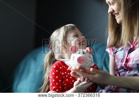 Portrait Of Smiling Attractive Funny Toddler Sitting On Couch Indoors. Cute Kid Saving Up For Future