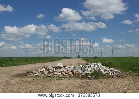 A Large Pit On A Poor Unsworned Rural Road Littered With Broken Brick Fragments, Stones, Constructio