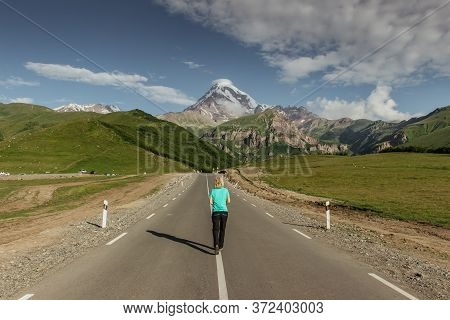 Young Girl On Her Way To The Mount Kazbeg,the Peak In Georgia. Girl In The Mountains. Hiking In The 