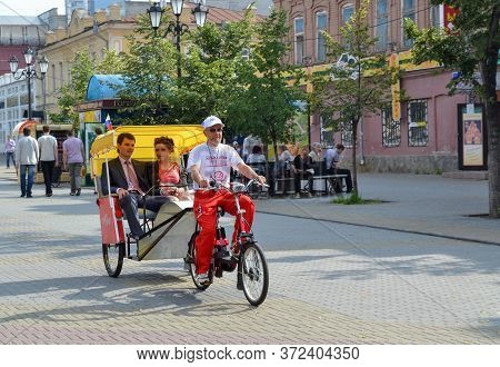 Chelyabinsk Russia July 16 2011 a Bicycle rickshaw rides a couple of lovers along a pedestrian street in the city center