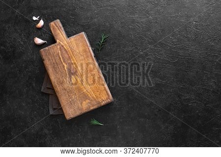 Empty Wooden Cutting Board On Black Stone Kitchen Table, Top View, Flat Lay. Wooden Platter, Copy Sp