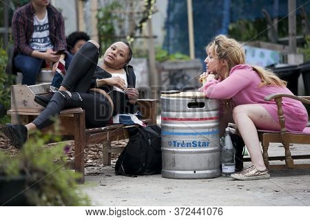 London, Uk - 17 July 2019, Nomadic Community Garden. Communal Garden Party. Two Girls Are Sitting In