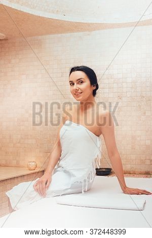Woman Resting In Hamam . She Sitting On A Marble Massage Table And Enjoying Hammam. Body Recovery At