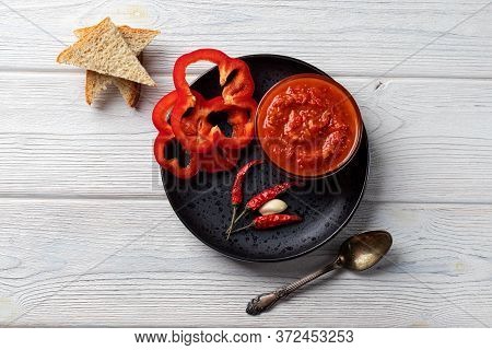 Ajvar Or Pindjur Red Vegetable Sauce, Paprika Pepper On A Black Plate And Wooden Table. Serbian Trad