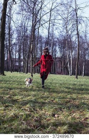 Pretty Young Girl In Redd Coat Playing With Dog Outside In Green Park, Lifestyle People Concept