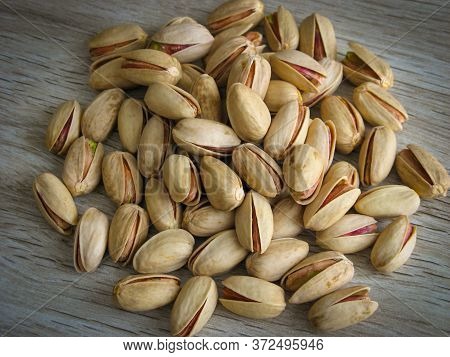 Close Up Of Iranian Export Pistachios On Wooden Background. Pistachio Is A Healthy Vegetarian Protei