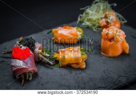 Sushi, Traditional Japanese Cuisine. Several Delicious Sushi On The Decorated Plate, Black Backgroun