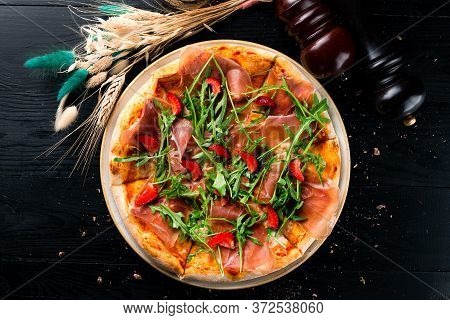 Pizza With Prosciutto Parma Ham, Arugula Salad Rocket And Strawberries On Wooden Background Italian 