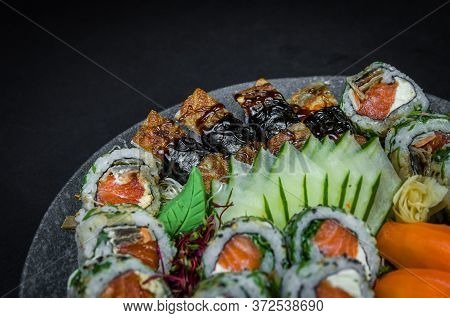 Sushi, Traditional Japanese Cuisine. Several Delicious Sushi On The Decorated Plate, Black Backgroun