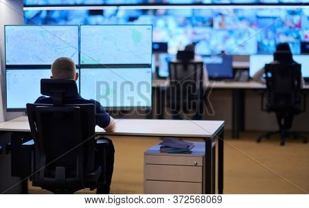 Male security operator working in a data system control room offices Technical Operator Working at  workstation with multiple displays, security guard working on multiple monitors  Male computer opera