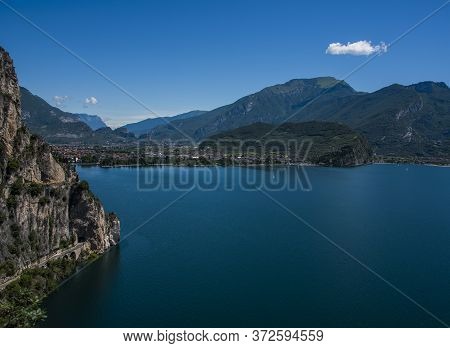 Beautiful View Of Lake Garda From The Ponale Road, With The Blue Sky, Sailing Boats, And The Green O