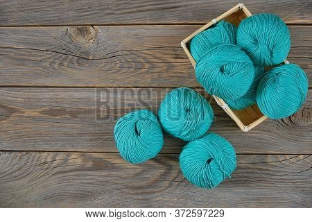 Colored Balls Of Yarn For Knitting Lie In A Wicker Basket On Wooden Background Top View