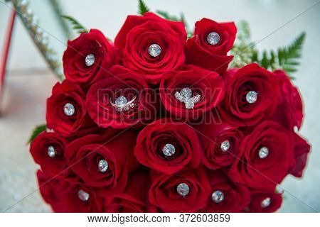 Set Of Wedding Rings In Red Rose Taken Closeup . Bride And Groom Rings On A Red Wedding Bouquet. A B