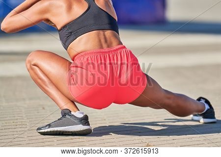Young Woman Warming Up Before Running Marathon. Beautiful Girl With Tan Legs. Outdoor Fitness Stretc