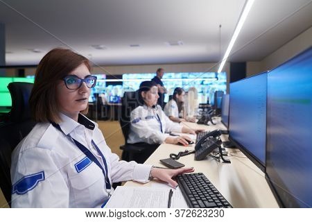 Group of Security data center operators working in a CCTV monitoring room looking on multiple monitors  Officers Monitoring Multiple Screens for Suspicious Activities  Team working on the System Contr