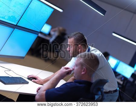 Male security operators working in a data system control room offices Technical Operator Working at  workstation with multiple displays, security guard working on multiple monitors  Male computer oper