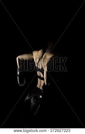 Female Boxer Training In The Dark Ring. Silhouette. Boxing Concept. Fighter Woman Back View Fist Clo