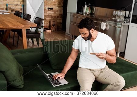 Bea Rded African American Man Holding Credit Card Near Laptop While Online Shopping In Living Room