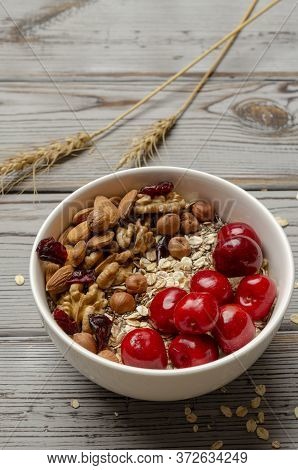 Bowl Of Oat Granola With Freshberries And Nuts On White Wooden Board For Healthy Breakfast