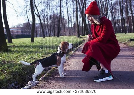 Pretty Young Girl In Redd Coat Playing With Dog Outside In Green Park, Lifestyle People Concept
