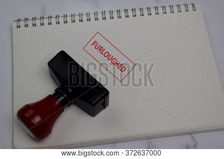 Red Handle Rubber Stamper And Furloughed Text Isolated On The Table.