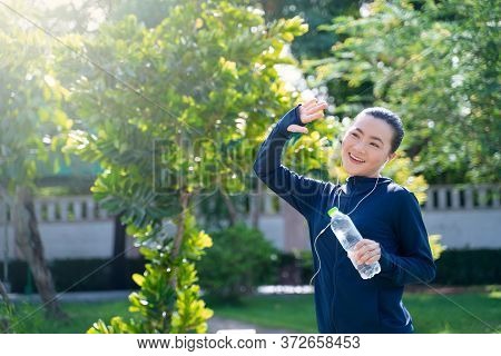 Portrait Of Asian Woman Workout Before Running At Village Park. Cheerful Runner Stretching And Warmi