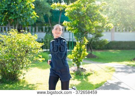 Portrait Of Asian Woman Workout Before Running At Village Park. Cheerful Runner Stretching And Warmi