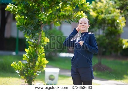 Portrait Of Asian Woman Wearing Earphones Listening To Music Was Sick With Fever At Park. Woman Exer