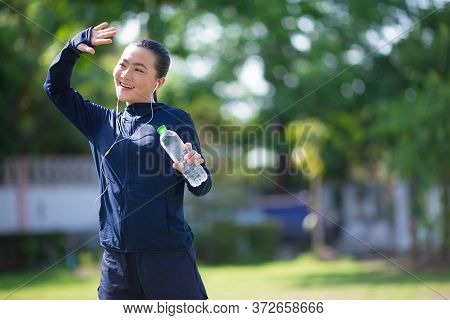 Portrait Of Asian Woman Wearing Earphones Listening To Music Was Sick With Fever At Park. Woman Exer